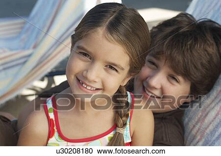Stock Image - Girl and boy on deck chair, portrait. Fotosearch