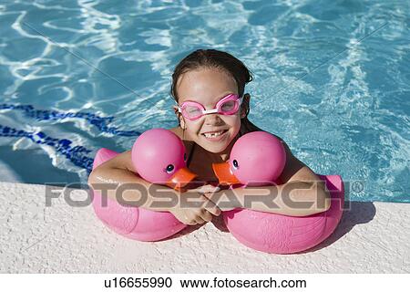 Stock Image - Girl at Pool Side Holding Pink Rubber Ducks. Fotosearch