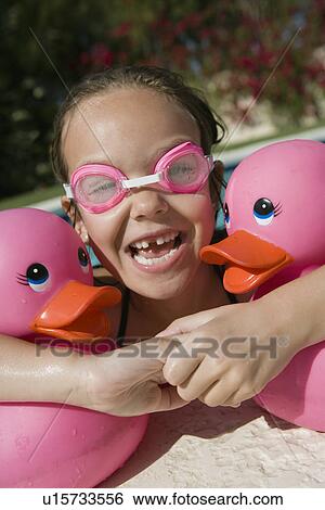 Stock Photograph - Girl at Pool Side Holding Pink Rubber Ducks. Fotosearch