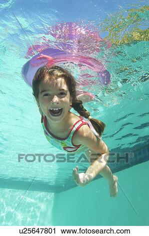 Stock Image - Girl holding inflatable raft underwater in swimming pool, portrait. Fotosearch