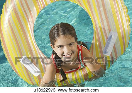 Stock Image - Girl in inflatable raft in swimming pool, portrait. Fotosearch