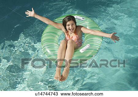 Stock Image - Girl in inflatable raft in swimming pool, portrait. Fotosearch