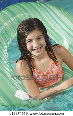 Stock Photo - Girl in inflatable raft in swimming pool, portrait. Fotosearch