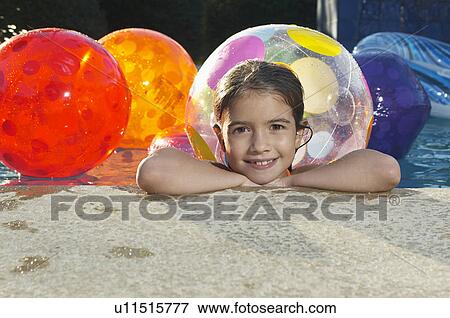 Girl in swimming pool with assortment of beach balls, portrait View Large Photo Image Stock Photo - Girl in swimming pool with assortment of beach balls, portrait. Fotosearch