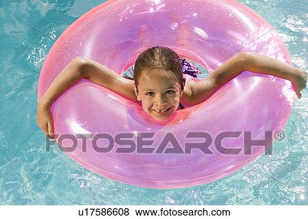 Stock Photo - Girl Inside Pink Float Tube in Pool. Fotosearch