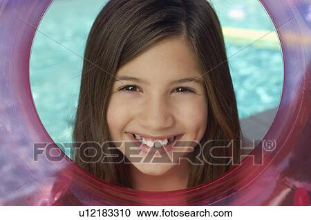 Stock Image - Girl looking through inflatable raft by water, portrait. Fotosearch