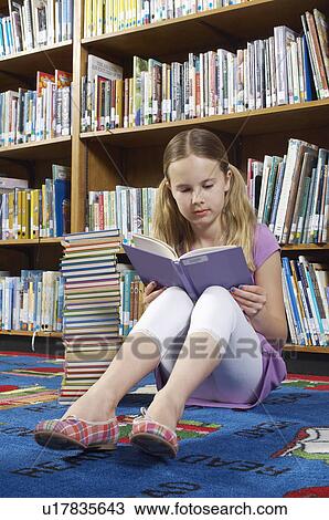 Girl sitting on the floor and reading book in library View Large Photo Image Stock Image - Girl sitting on the floor and reading book in library. Fotosearch