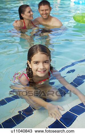 Stock Image - Girl with parents in swimming pool, portrait. Fotosearch