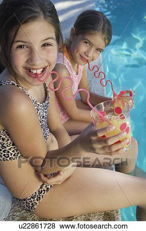 Girls drinking juice from crazy straws on edge of swimming pool, portrait View Large Photo Image Stock Photo - Girls drinking juice from crazy straws on edge of swimming pool, portrait. Fotosearch