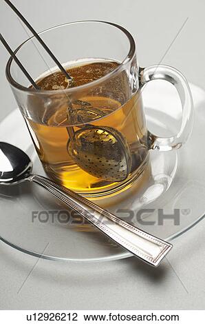 Stock Image - Glass with tea strainer inside, close-up. Fotosearch