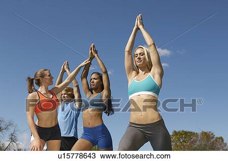 Stock Image - Group exercising with instructor in park. Fotosearch