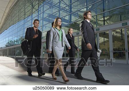Stock Photo - Group of business people walking past office building. Fotosearch