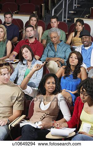 Picture - Group of people in classroom, one woman with raised arm. Fotosearch
