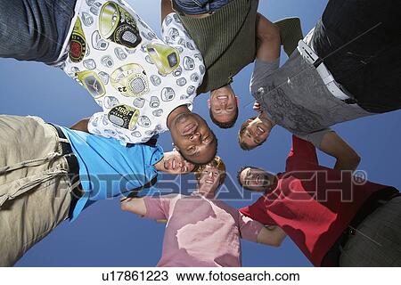 Stock Image - Group of young men in circle, view from below. Fotosearch