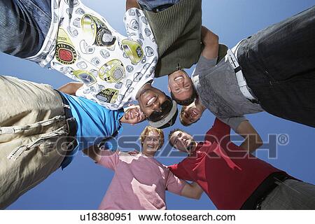 Stock Image - Group of young men in circle, view from below. Fotosearch