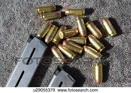 Stock Photo - Gun magazine and bullets on carpet, close-up. Fotosearch
