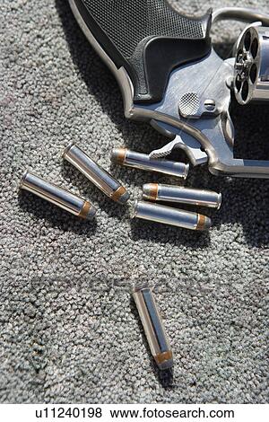 Stock Photo - Hand gun and bullets on carpet, close-up. Fotosearch