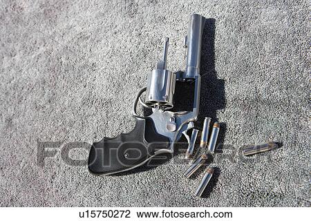 Stock Image - Hand gun and bullets on carpet. Fotosearch