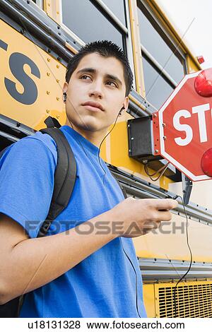 Stock Photo - High School Boy With MP3 Player by School Bus. Fotosearch