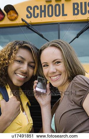 High School Girls Listening to Cell Phone by School Bus View Large Photo Image Stock Image - High School Girls Listening to Cell Phone by School Bus. Fotosearch