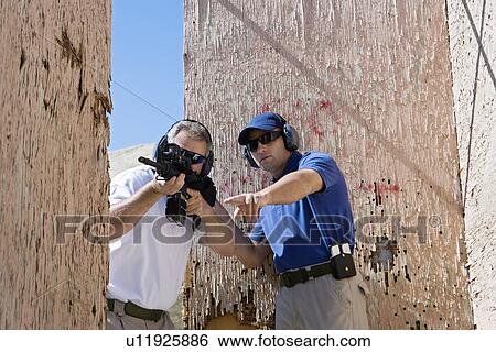 Instructor assisting man aiming machine gun at firing range View Large Photo Image Stock Photograph - Instructor assisting man aiming machine gun at firing range. Fotosearch