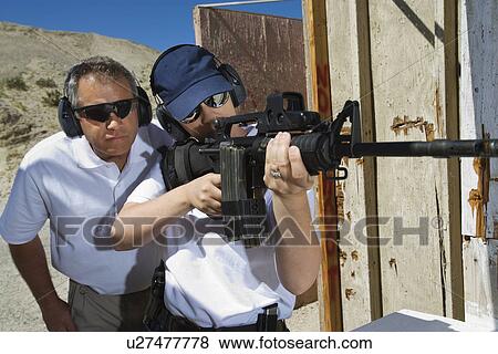 Instructor assisting woman aiming machine gun at firing range View Large Photo Image Stock Photo - Instructor assisting woman aiming machine gun at firing range. Fotosearch