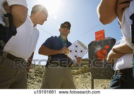 Stock Image - Instructor holding clipboard with target diagram at combat training. Fotosearch