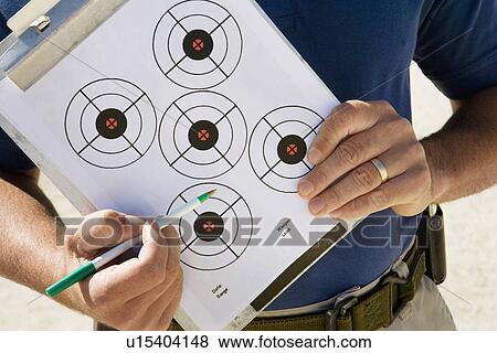 Stock Photo - Instructor holding clipboard with target diagram, mid section. Fotosearch