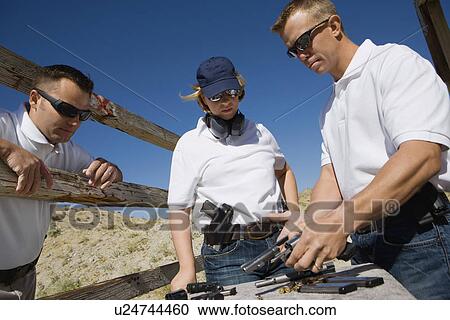 Instructor loading gun for man and woman at firing range View Large Photo Image Stock Image - Instructor loading gun for man and woman at firing range. Fotosearch