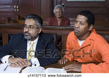 Stock Image - Lawyer and criminal sitting in court. Fotosearch