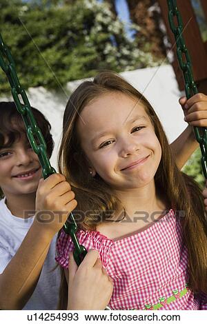 Stock Image - Little Boy Swinging Girl. Fotosearch