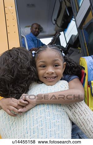 Stock Photo - Little Girl Hugging Her Mother Beside the Schoolbus. Fotosearch