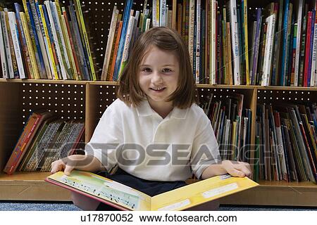 Stock Image - Little Girl Reading in the Library. Fotosearch