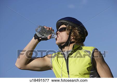 Male cyclist drinking from water bottle, outdoors View Large Photo Image Stock Photo - Male cyclist drinking from water bottle, outdoors. Fotosearch