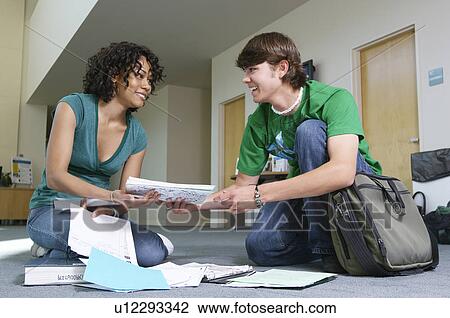 Male student assisting female student, picking up books from floor View Large Photo Image Stock Image - Male student assisting female student, picking up books from floor. Fotosearch