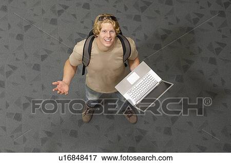 Male student holding laptop, indoors, portrait View Large Photo Image Stock Photo - Male student holding laptop, indoors, portrait. Fotosearch