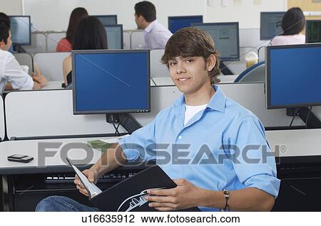 Stock Image - Male student sitting in computer classroom, portrait. Fotosearch