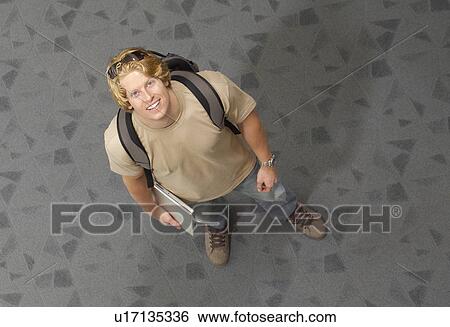 Stock Photograph - Male student smiling, indoors, portrait. Fotosearch