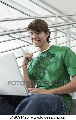 Male student using laptop on stairs, portrait View Large Photo Image Stock Image - Male student using laptop on stairs, portrait. Fotosearch