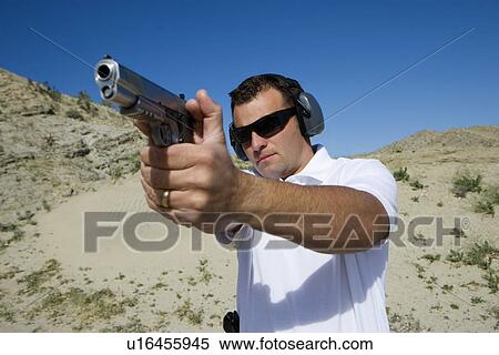 Man aiming hand gun at firing range in desert View Large Photo Image Stock Photography - Man aiming hand gun at firing range in desert. Fotosearch