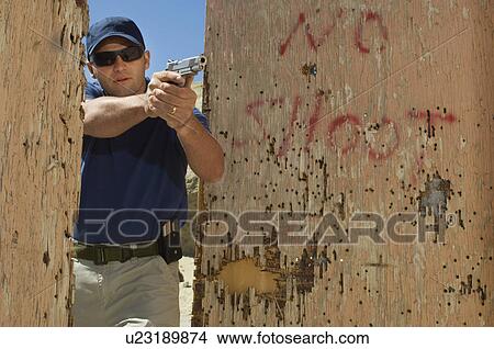 Man aiming hand gun at firing range View Large Photo Image Picture - Man aiming hand gun at firing range. Fotosearch