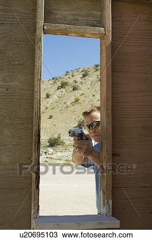 Man aiming hand gun at firing range View Large Photo Image Stock Image - Man aiming hand gun at firing range. Fotosearch