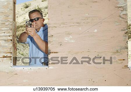 Stock Photography - Man aiming hand gun at firing range. Fotosearch