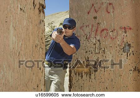 Man aiming hand gun at firing range View Large Photo Image Stock Photography - Man aiming hand gun at firing range. Fotosearch