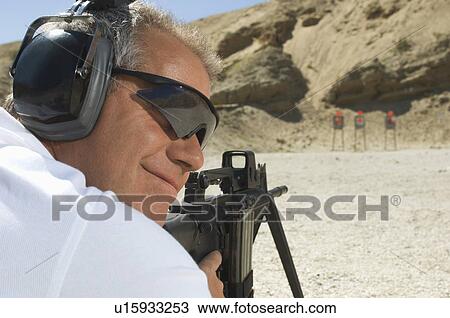 Man aiming machine gun at firing range View Large Photo Image Stock Image - Man aiming machine gun at firing range. Fotosearch