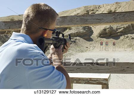 Stock Photo - Man aiming machine gun at firing range. Fotosearch