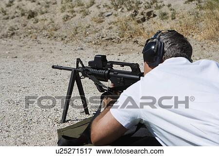Stock Photo - Man aiming machine gun at firing range. Fotosearch