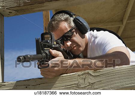 Man aiming machine gun at firing range View Large Photo Image Stock Photograph - Man aiming machine gun at firing range. Fotosearch