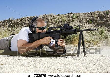 Man aiming machine gun at firing range View Large Photo Image Stock Photography - Man aiming machine gun at firing range. Fotosearch