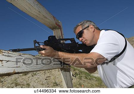 Man aiming rifle at firing range View Large Photo Image Picture - Man aiming rifle at firing range. Fotosearch